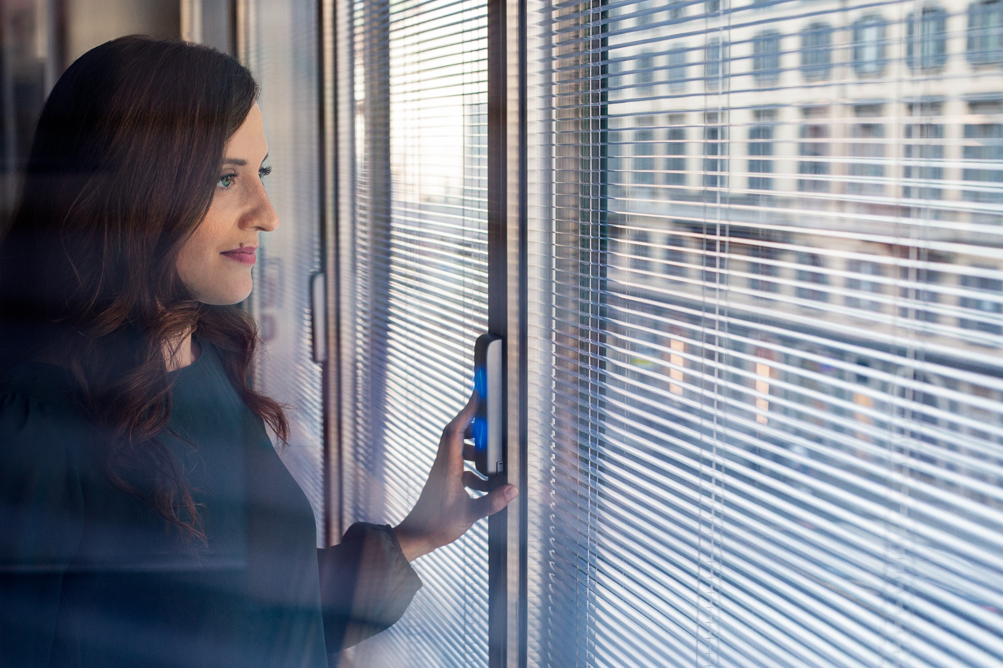 Person operating an integrated blind beside a window